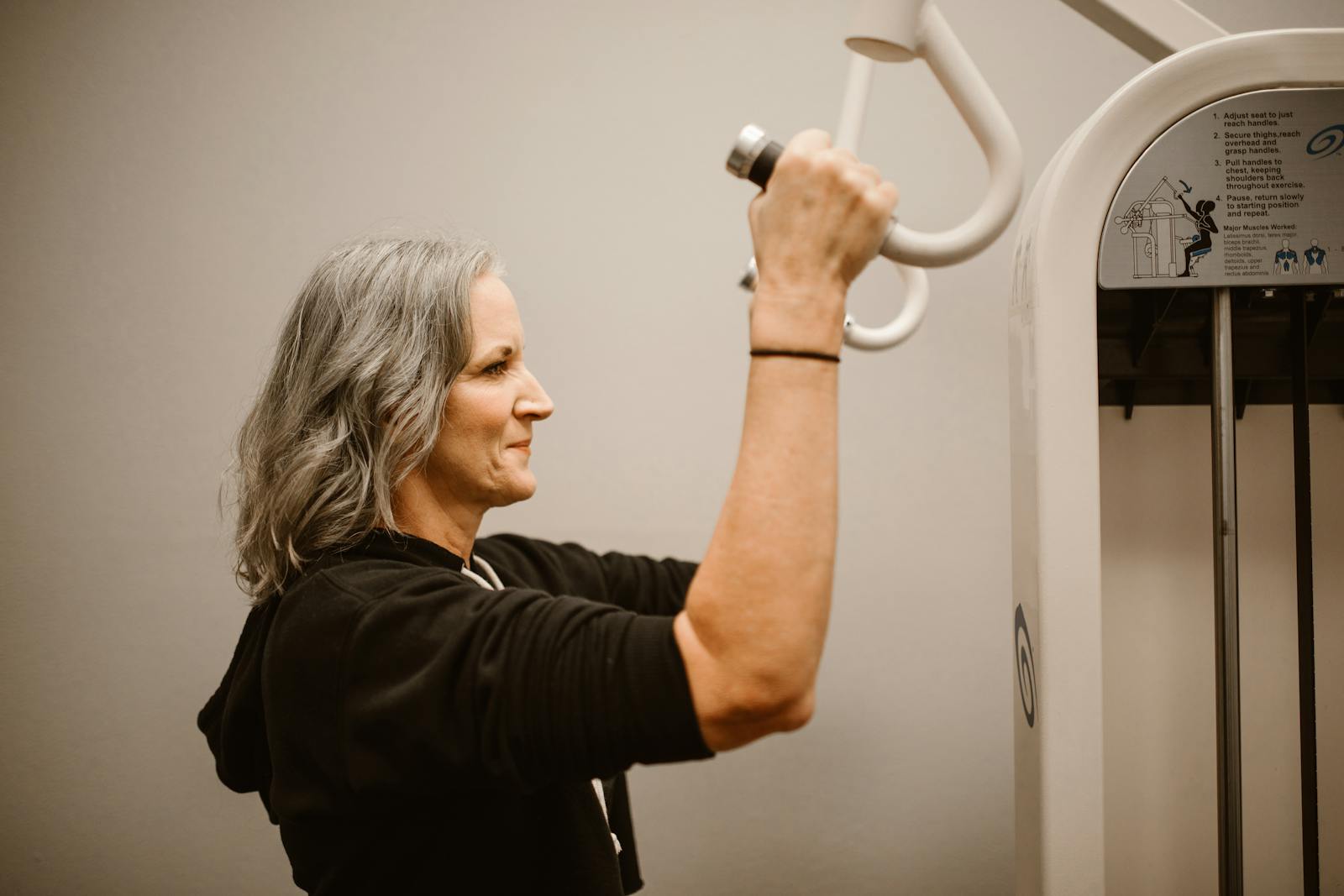 Active senior woman working out on gym equipment, focusing on strength and wellness.