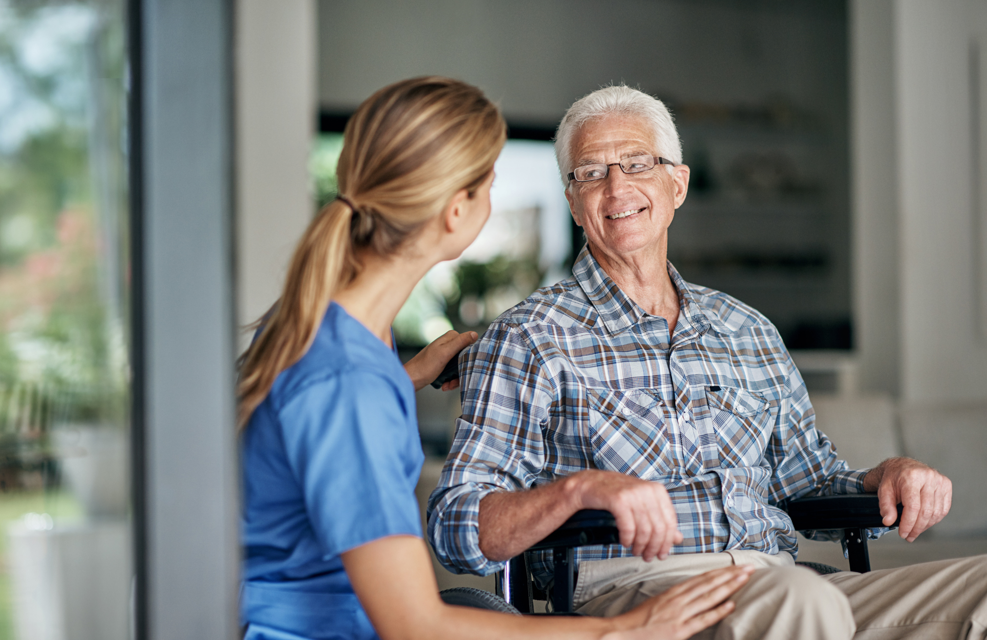 caregiver helping an older man in a wheelchair